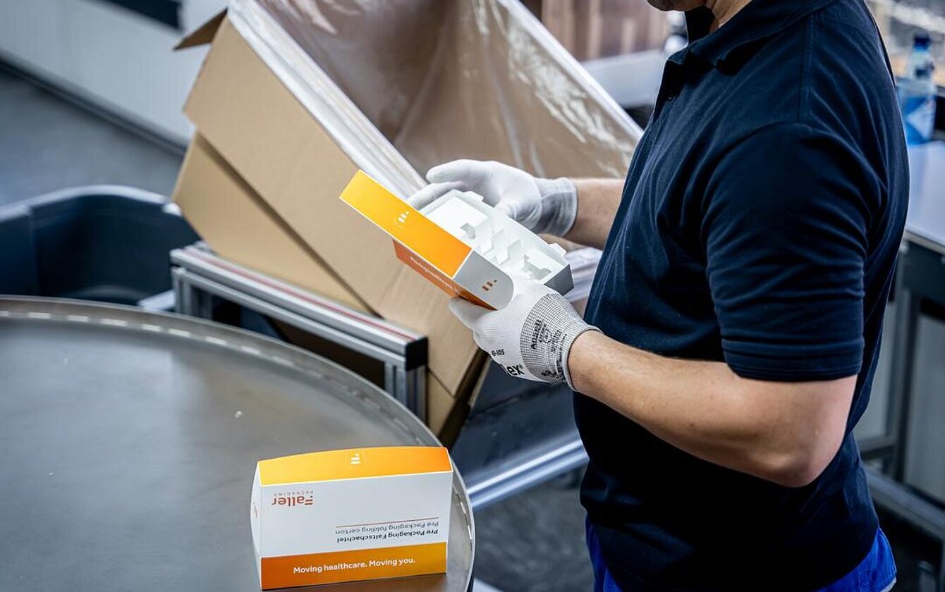 Quality control in the PrePackaging Service by Faller Packaging – employee inspecting pre-packaged folding cartons.
