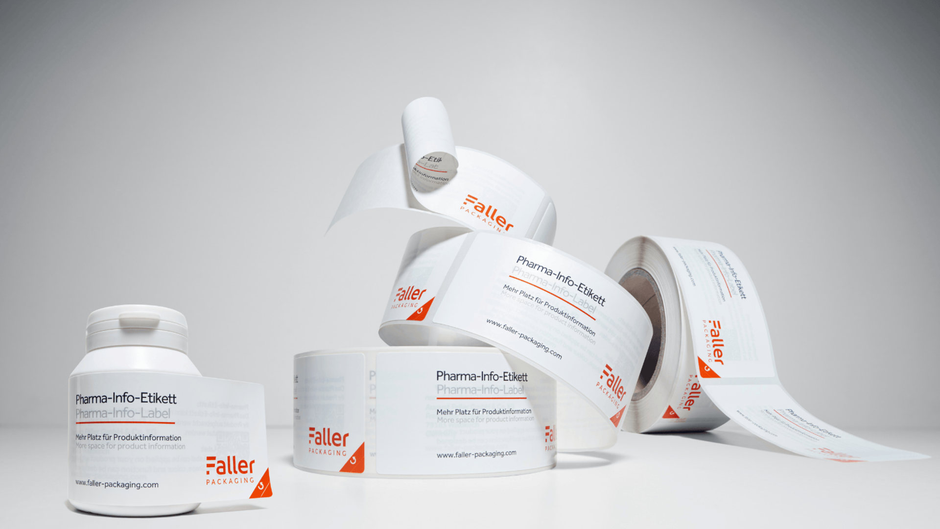 Rolki etykiet samoprzylepnych do informacji farmaceutycznych, ułożone na neutralnym tle. Etykiety są wyraźnie oznaczone i przedstawiają markę Faller.