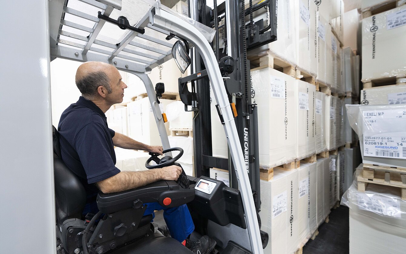 Chauffør af gaffeltruck Logistikmedarbejder på lageret opbevarer paller med gaffeltruck