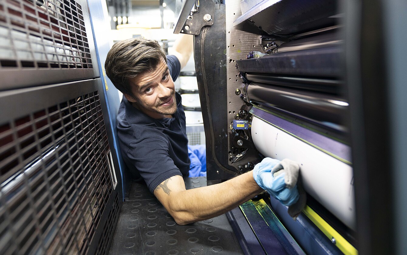 Emballageteknolog trykmaskine Emballageteknolog justerer blæk i trykmaskinen