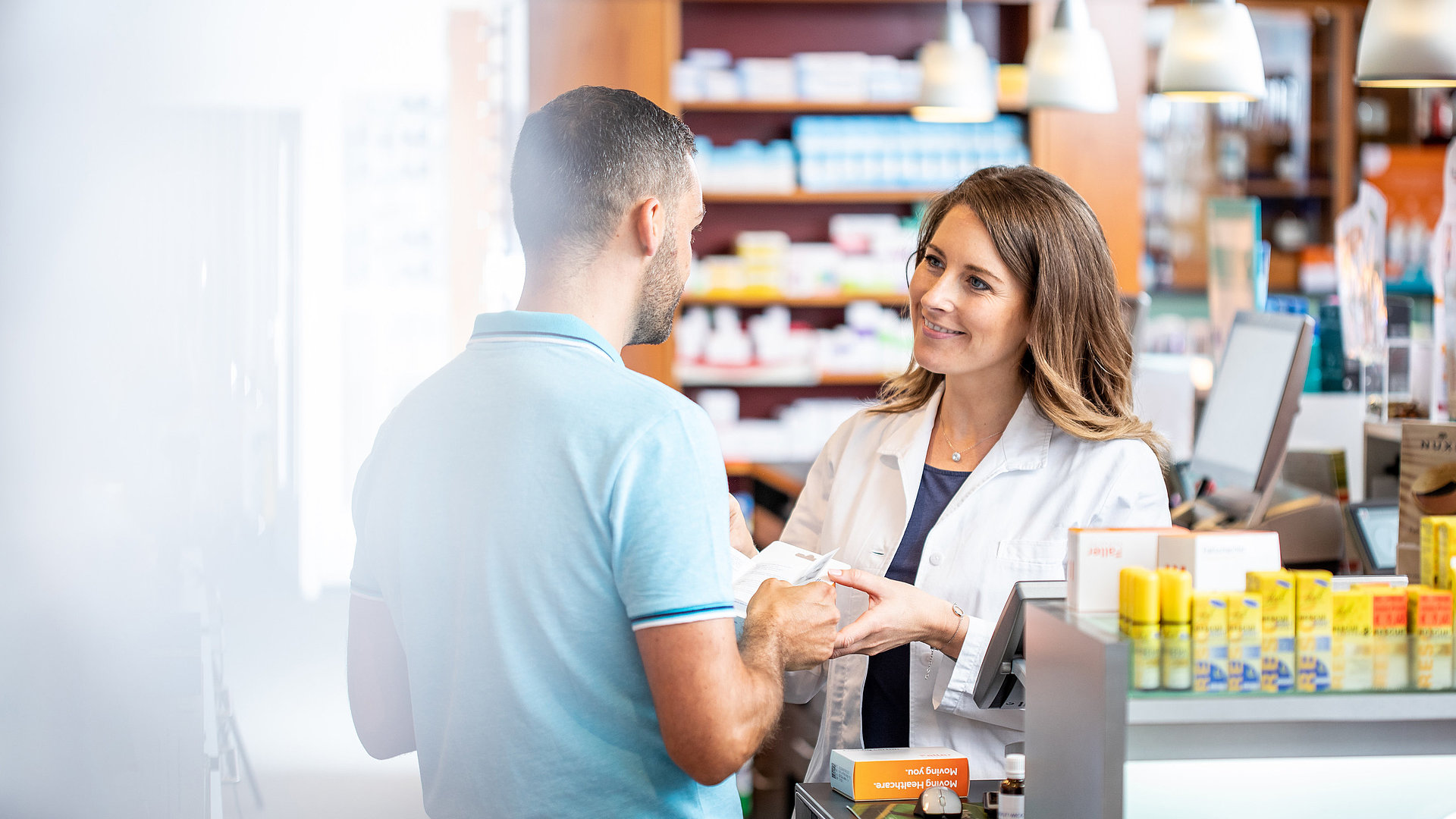 Pharmacienne conseillant un client sur les emballages de médicaments – solutions Faller Packaging pour plus de compliance et de commodité au quotidien.